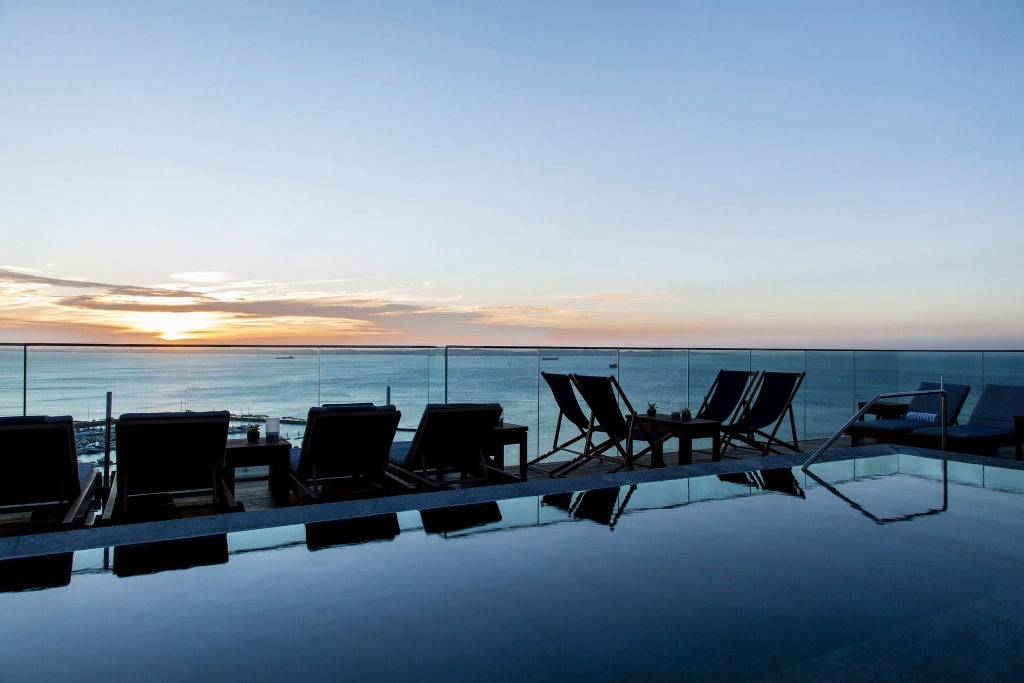 Elegant modern hotel facade with sleek architecture, tropical palm trees, and luxurious design overlooking the scenic coastline of Salvador, Brazil.