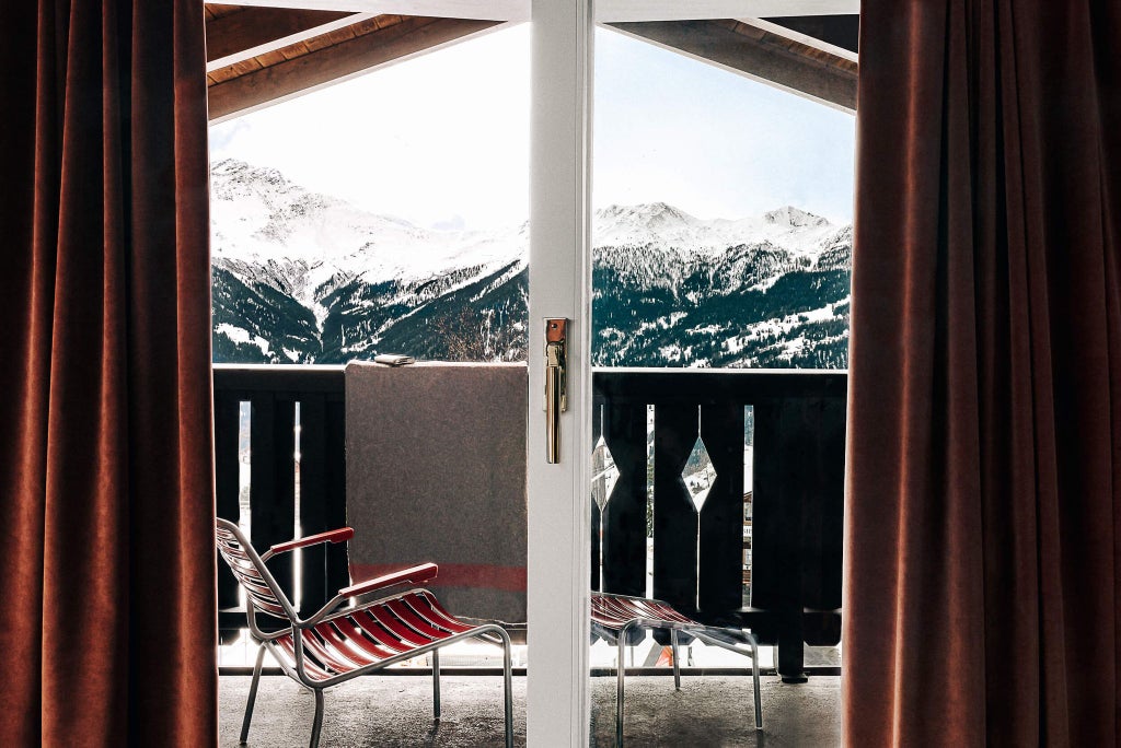 Luxurious alpine suite with panoramic mountain views, featuring contemporary design, elegant wood paneling, and expansive floor-to-ceiling windows overlooking Swiss landscape