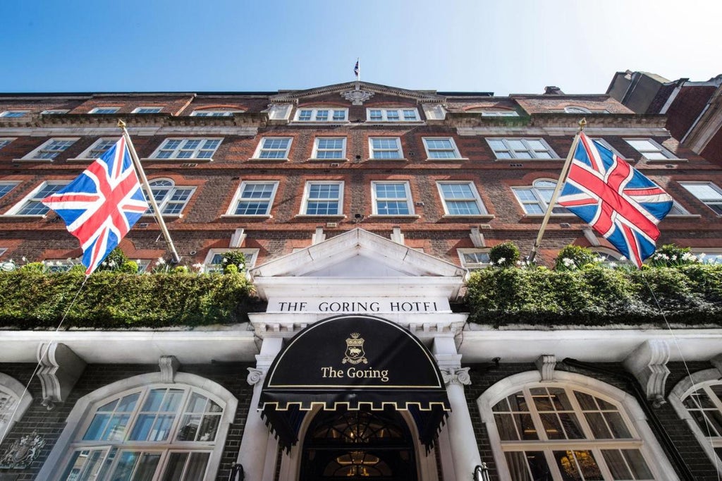 A prestigious five-star Edwardian hotel featuring grand white stone facade, ornate balconies and iconic red awnings in central London.