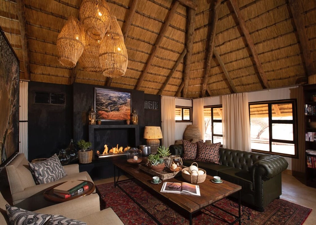 Luxurious desert lodge with thatched-roof chalets nestled among red sand dunes, featuring private plunge pools and panoramic windows