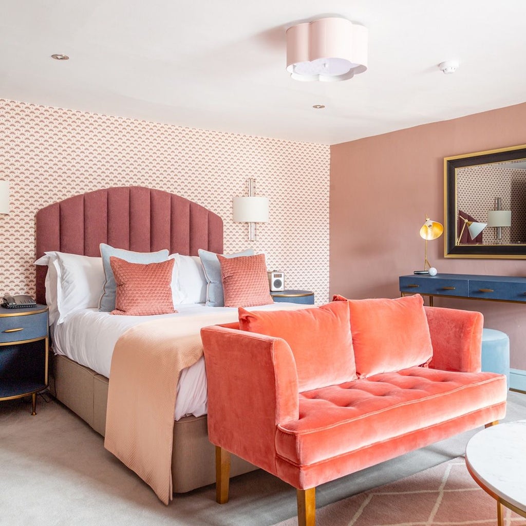 Elegant classic hotel room with plush white bedding, soft cream walls, tasteful artwork, and polished wooden furnishings at a luxury UK boutique hotel