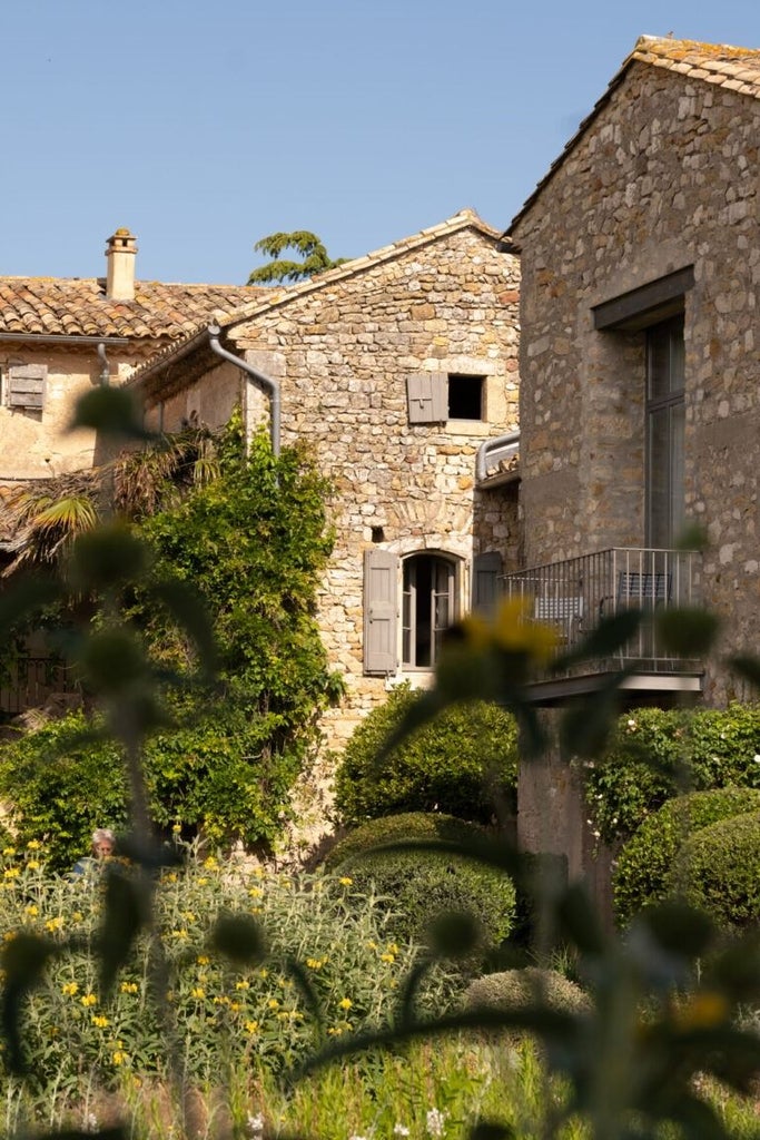 Elegant stone-walled boutique hotel nestled in Provençal countryside, stone terrace with lavender, sunlit stone facade, rustic luxury ambiance