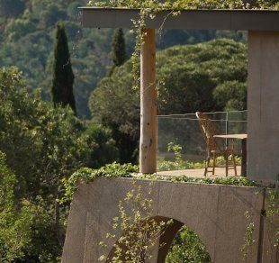 Contemporary cliffside hotel in St Tropez with infinity pool overlooking Mediterranean Sea, surrounded by lush gardens at sunset