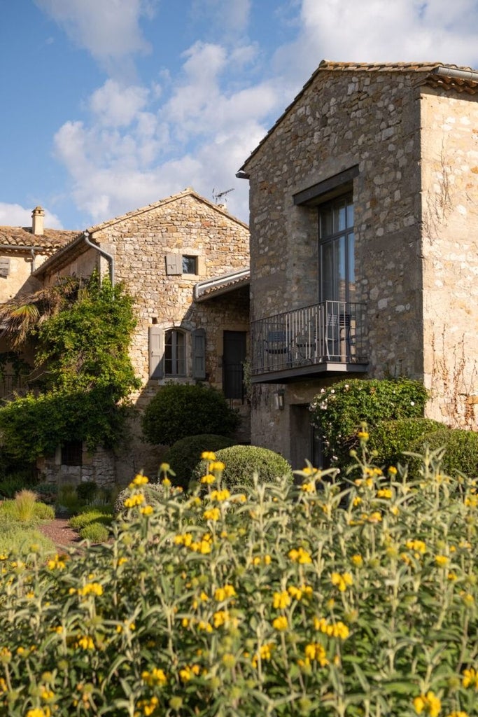 Rustic stone hotel nestled in Provençal countryside, with lavender fields, limestone walls, and elegant terrace overlooking rolling French landscape