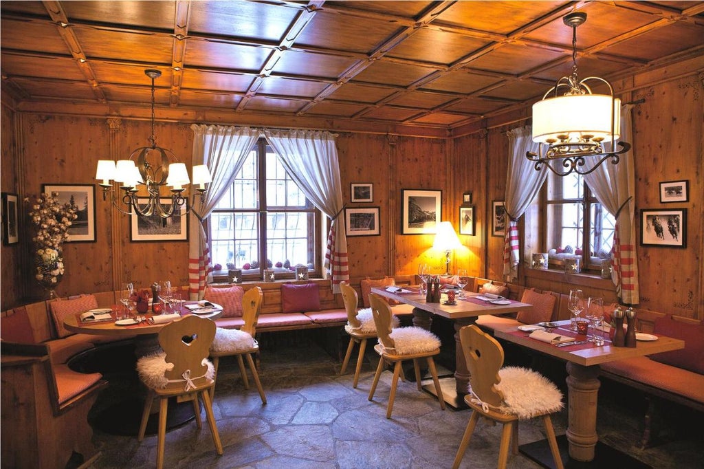 Luxurious mountain lodge Hotel Giardino Mountain with snow-capped Alps backdrop, featuring timber balconies and traditional Swiss architecture