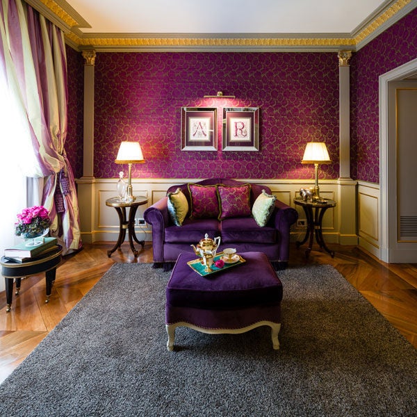 Luxurious hotel suite with ornate gold-framed mirrors, crystal chandelier, antique furniture, and high frescoed ceilings in Villa Cora, Florence