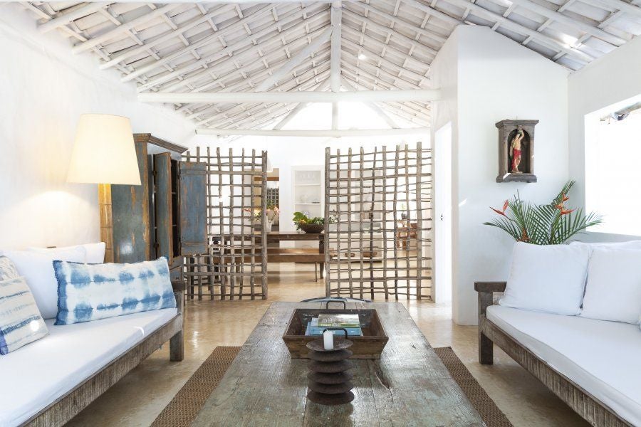 Rustic wooden bed with white linens in a luxurious Brazilian eco-resort room, featuring warm natural light and traditional Bahian design elements at UXUA Casa Hotel