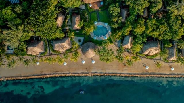 Elegant boutique hotel room with rustic wooden furniture, white linens, and a serene view of lush tropical gardens in Argentina's hidden retreat