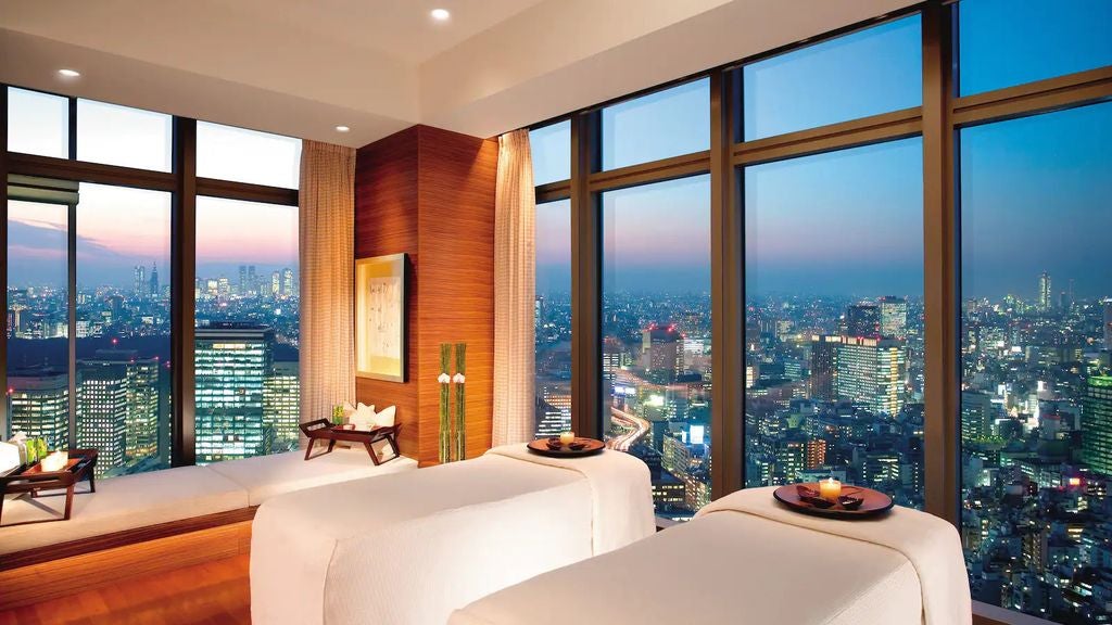 Luxurious Mandarin Oriental Tokyo hotel exterior at dusk, featuring glass facade, city lights, and dramatic Mt. Fuji backdrop