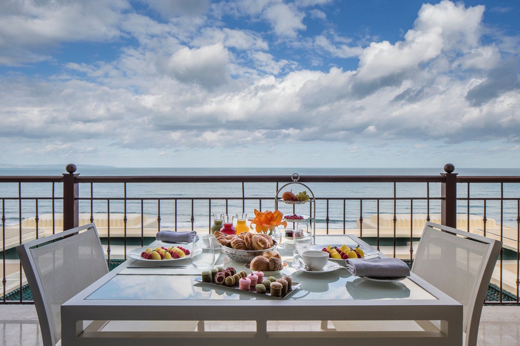 Modern luxury beachfront hotel with white Mediterranean architecture, palm-lined pools, and panoramic views of the Gulf of Tunis