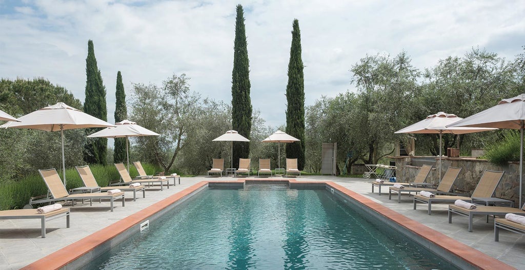 Elegant Tuscan villa with stone facade, surrounded by lush cypress trees and manicured gardens, golden sunlight highlighting its rustic Mediterranean charm