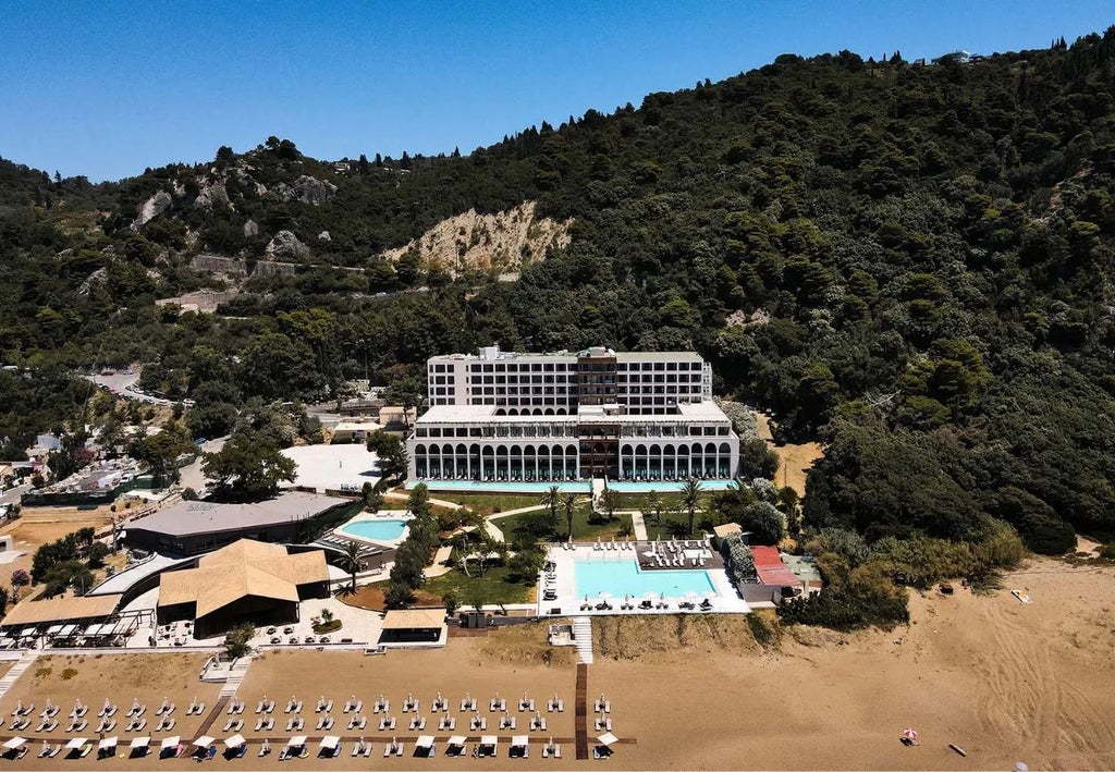 Luxurious beachfront resort with white dome architecture, azure Ionian Sea, and lush green landscape at Domes of Corfu, Greece