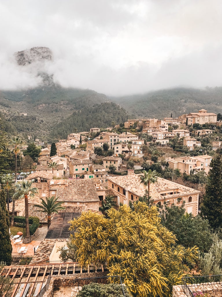 Elegant stone villa with terracotta roof nestled in Mallorca's Tramuntana mountains, featuring lush gardens and a tranquil pool terrace