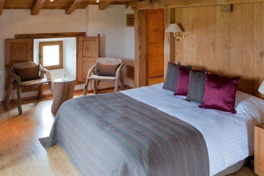 Lavish French countryside cottage bedroom with rustic wood floors, plush white linens, and elegant centaur artwork against soft natural lighting