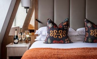 Elegant classic hotel room with plush queen bed, soft neutral decor, and sophisticated urban styling in a luxury United Kingdom boutique hotel setting