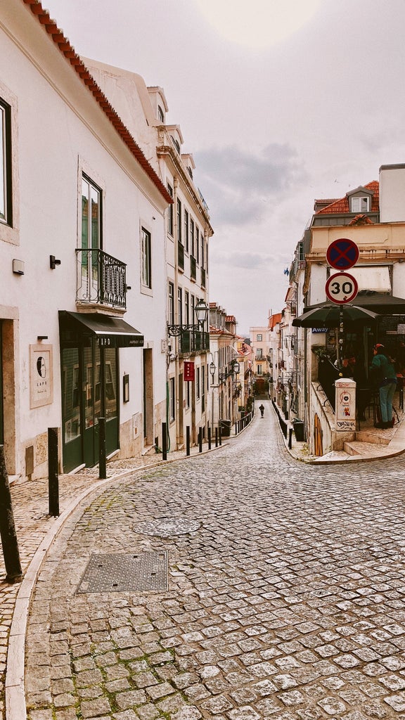 Colorful tuk tuk weaving through narrow, cobblestone streets of a historic Portuguese city with vibrant architecture and sunshine-drenched landscape