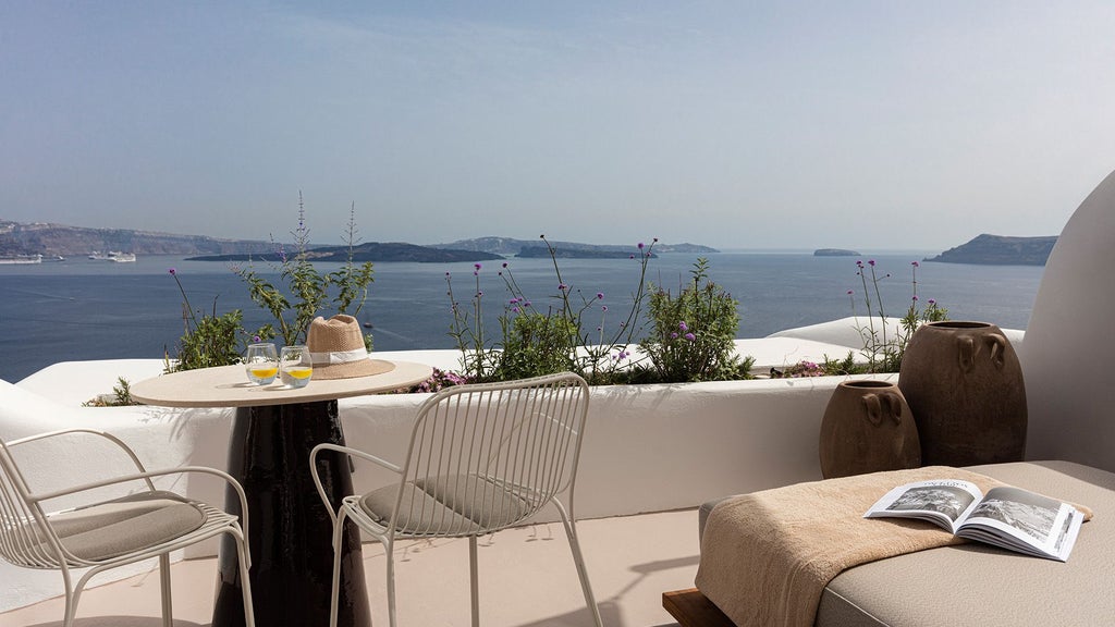 Luxurious white-washed Cycladic honeymoon suite with private infinity pool overlooking scenic blue Aegean waters in Oia, Santorini