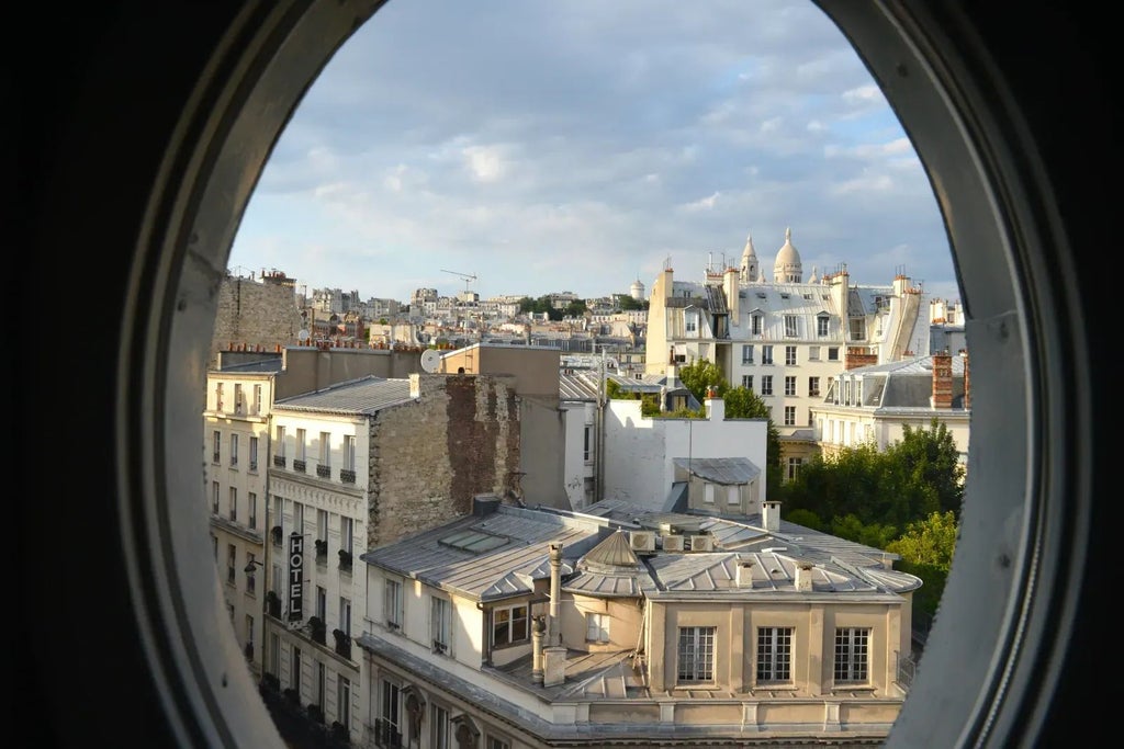 Elegant Parisian hotel room with plush bedding, vintage-inspired decor, rich burgundy walls, and sophisticated lighting at the Grand Pigalle Hotel