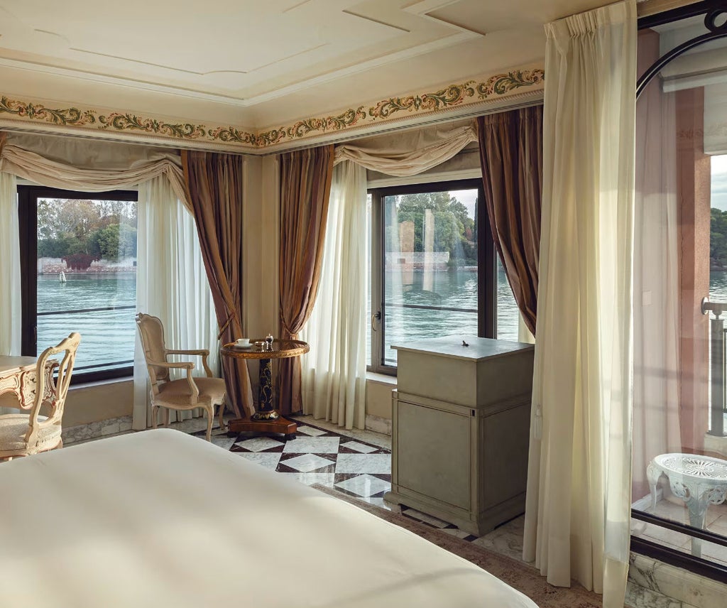 Opulent suite at Belmond Cipriani featuring ornate Venetian decor, crystal chandelier, silk drapes and panoramic lagoon views from balcony