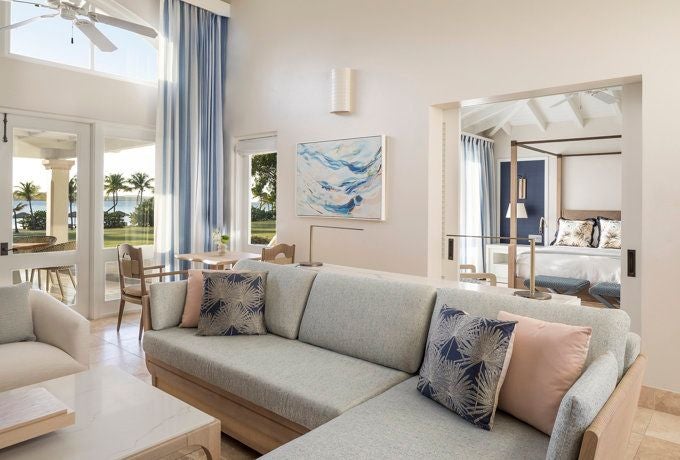 Elegant island retreat featuring pristine white linens, Caribbean-inspired decor, and expansive ocean views from a luxurious Junior Suite at Jumby Bay Resort, Antigua