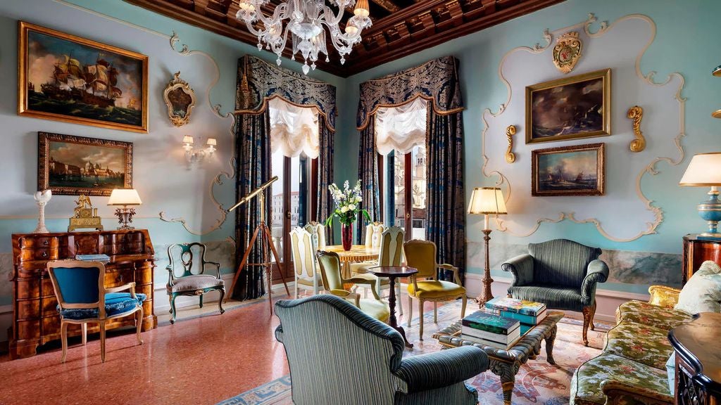 Opulent Venetian suite with silk damask walls, antique furnishings, crystal chandeliers, and panoramic Grand Canal views from tall windows