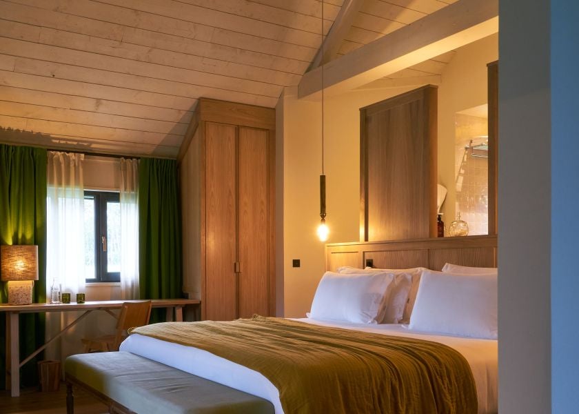 Elegant treehouse-style suite at Les Sources de Cheverny, featuring rustic wood interiors, plush bedding, and panoramic French countryside views through large windows