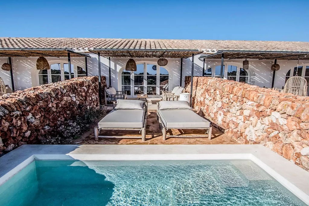 Luxurious swimming pool at Torre Vella resort in Spain, surrounded by elegant loungers with pristine blue waters and Mediterranean landscape backdrop