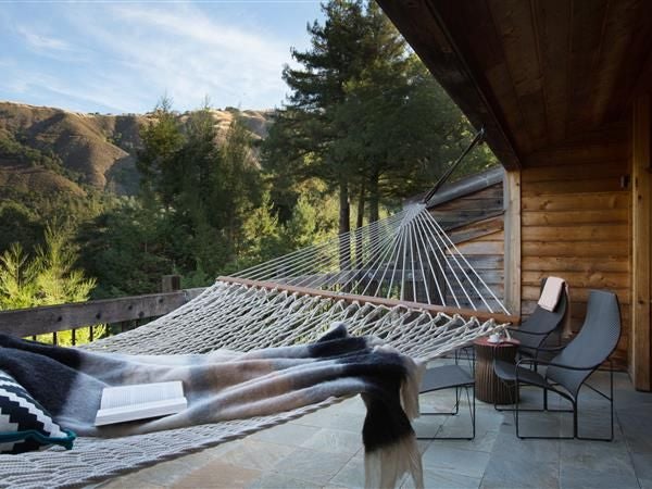 Luxurious cliffside resort with panoramic Pacific Ocean views, nestled in lush redwood forest at scenic Big Sur, showcasing rustic elegance and natural beauty