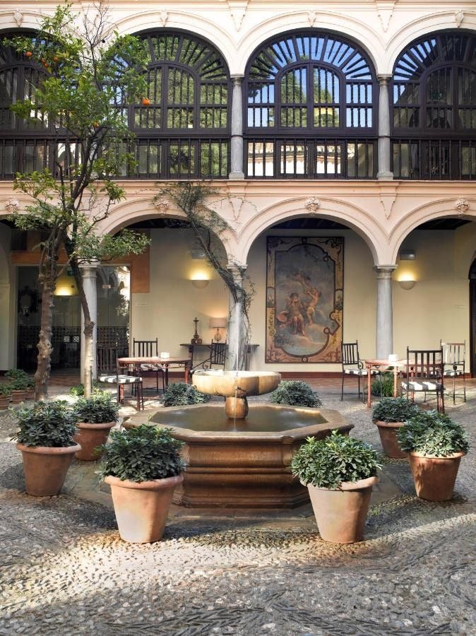 Historic Parador Granada hotel with ornate Moorish archways and columns, nestled within Alhambra palace grounds at sunset