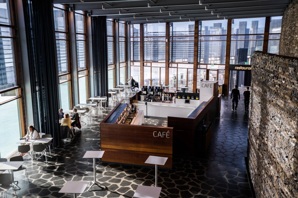 Luxurious minimalist hotel room with panoramic windows overlooking volcanic landscape, featuring sleek Nordic design and natural stone elements in Iceland