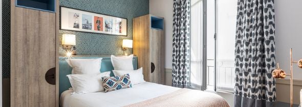 Elegant French hotel room with connecting doors, sophisticated neutral decor, wooden floors, and plush bedding in warm, inviting tones