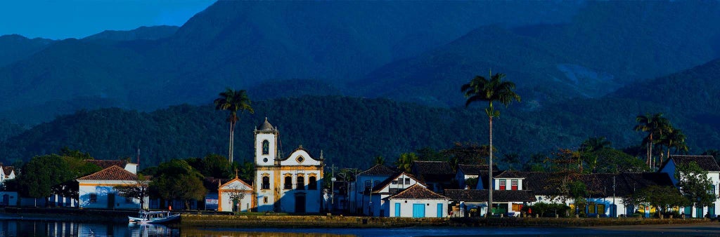 Luxurious boutique hotel with turquoise-blue facade, white colonial architecture, and elegant tropical courtyard in historic Paraty, Brazil