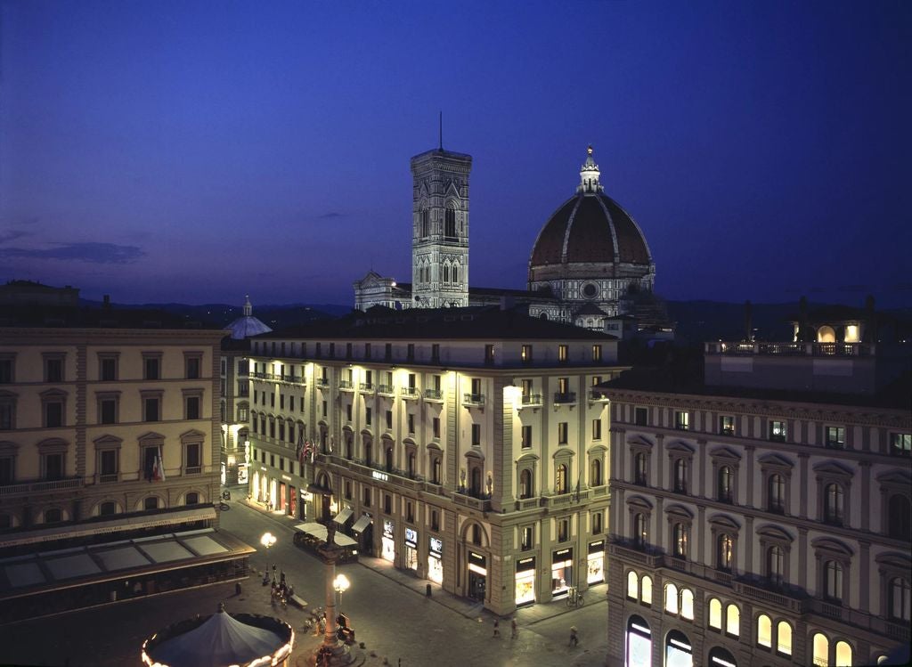 Elegant Italian hotel with ornate Renaissance facade, marble columns, gilded ironwork balconies, and Florentine architectural details