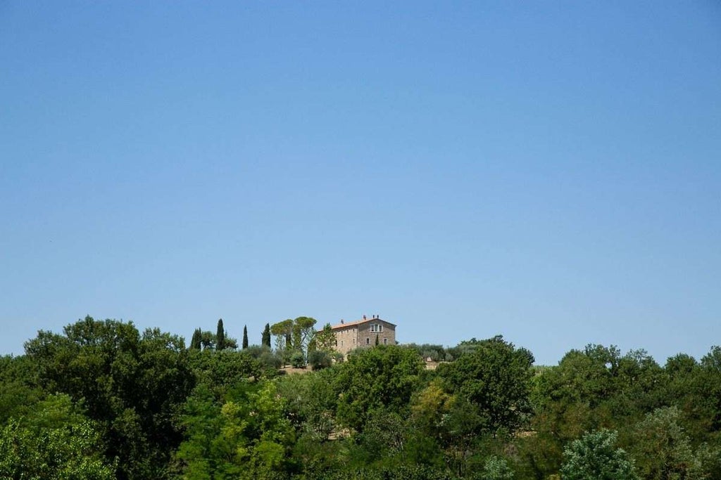 Elegant Italian villa with stone facade, panoramic balconies, and lush Mediterranean garden surrounded by cypress trees in sunlight