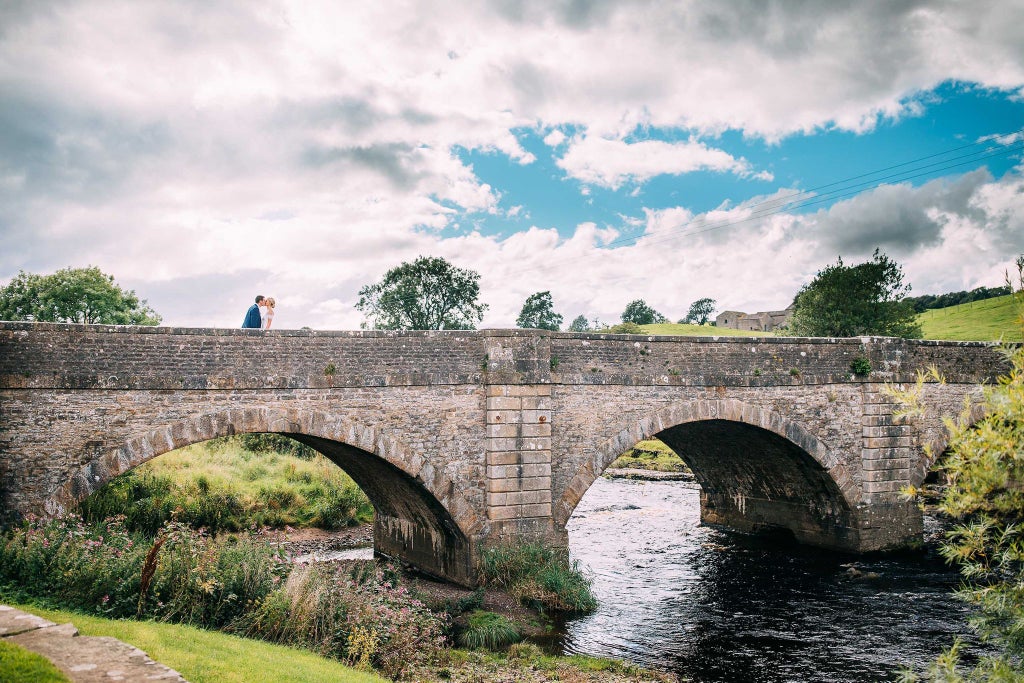 Elegant stone boutique hotel nestled in Yorkshire Dales, featuring classic architecture, manicured gardens, and a serene countryside backdrop with rolling green hills