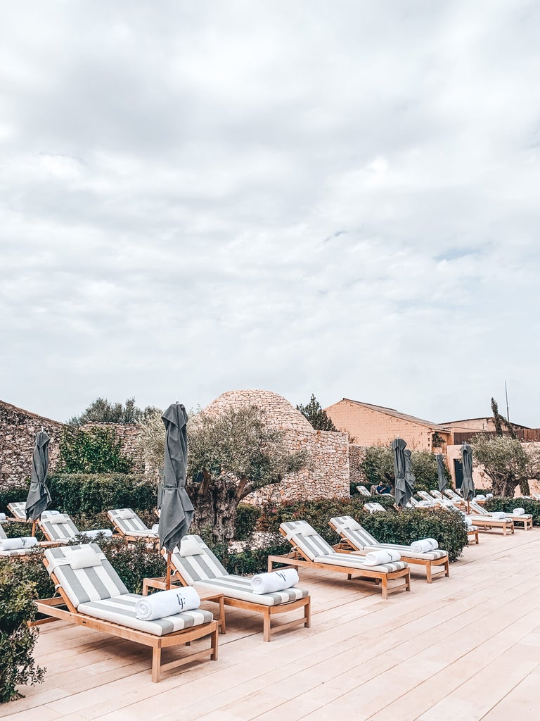 Elegant stone arched courtyard of luxury boutique hotel Can Ferrereta, featuring rustic Mediterranean architecture and potted olive trees