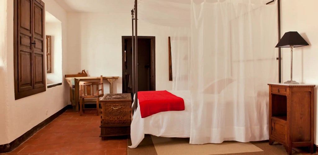 Rustic wooden interior of luxurious Spanish hotel room with exposed beams, vintage furniture, and soft natural light at Cortijo del Marqués