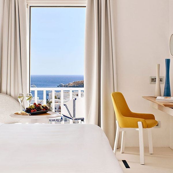 Luxurious white-themed bedroom with panoramic Aegean Sea view, minimalist design, crisp linens, and elegant coastal Greek island aesthetic