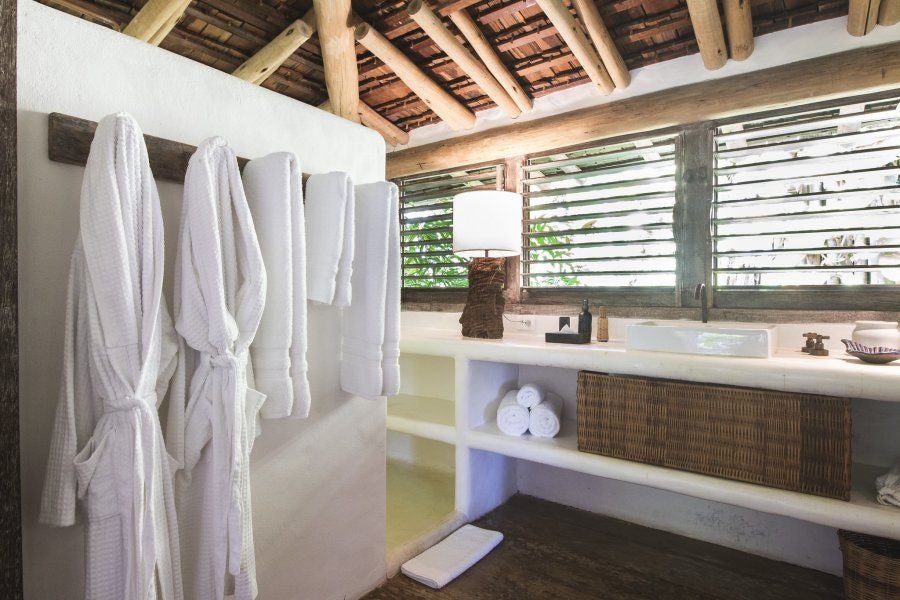 Luxurious Brazilian hotel room with traditional wooden furniture, vibrant textiles, and organic design blending colonial architecture with tropical aesthetic