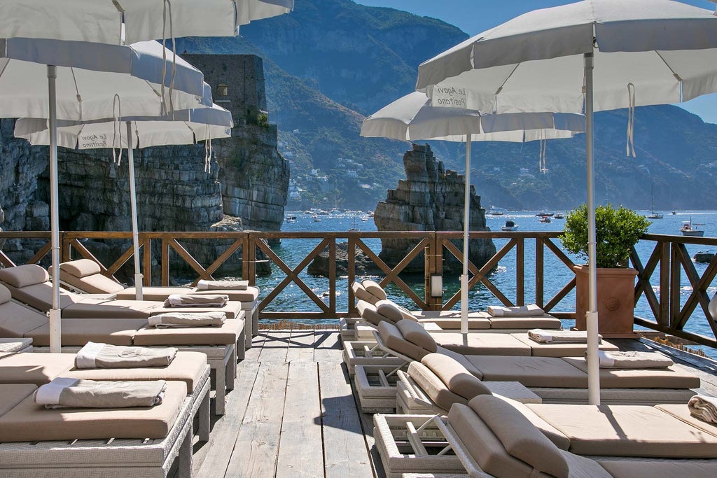 Terraced luxury hotel built into Italian cliffside overlooking Mediterranean Sea, with multiple levels of private balconies and infinity pools