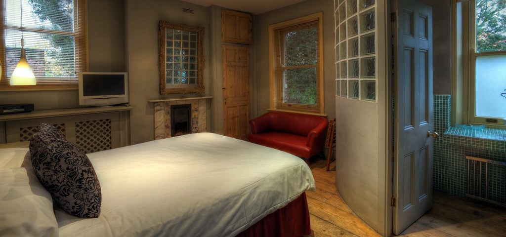 Elegant luxury suite with plush king bed, soft white linens, modern artwork, and sophisticated neutral color palette in boutique UK hotel room