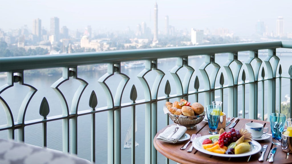 Opulent Five-star hotel rising along the Nile River in Cairo with illuminated facade, palm trees and grand entrance reflecting in water