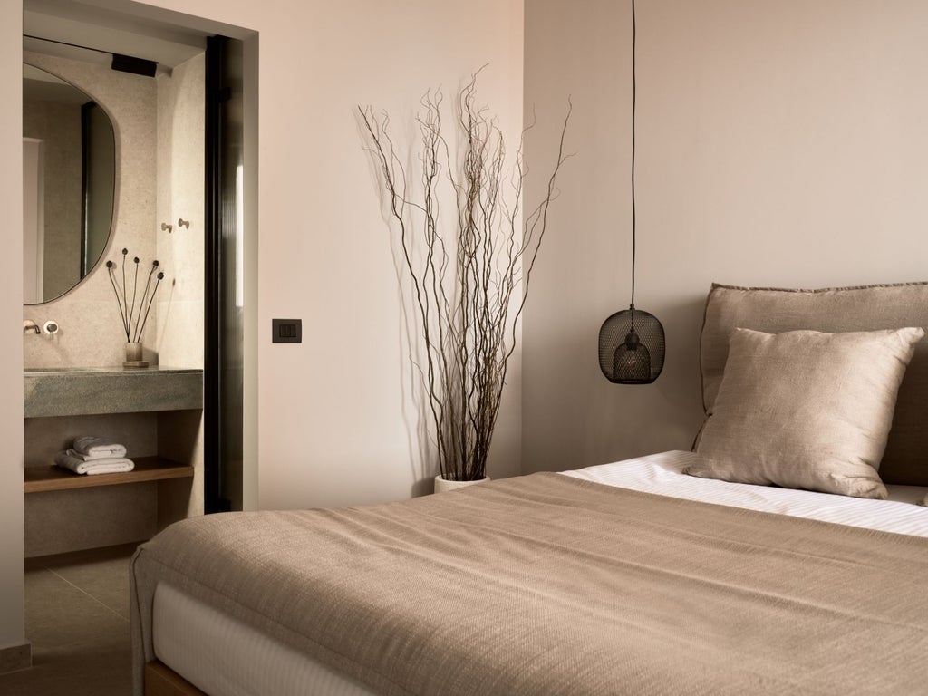 Spacious white-walled luxury villa bedroom with elegant wooden furniture, panoramic sea view, and minimalist design in Santorini, Greece