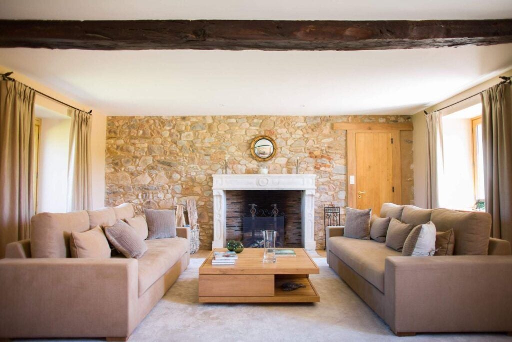 Rustic-chic French countryside cottage bedroom with exposed wooden beams, elegant linens, and panoramic views of lush green landscape at luxury Domaine des Etangs