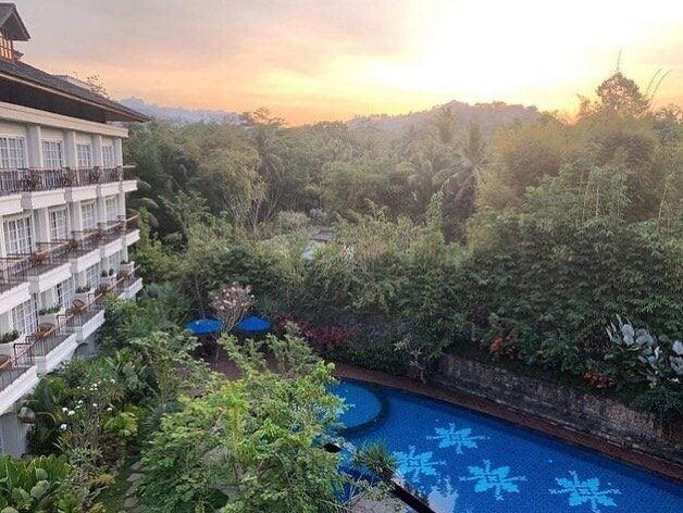 Luxury private villa with infinity pool overlooking lush jungle and distant mountains at sunset, featuring traditional Indonesian architecture