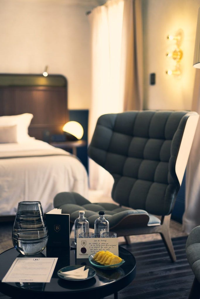 Opulent Deluxe Suite with antique furnishings, ornate wooden headboard, plush white bedding, and soft natural light casting elegant shadows in historic Spanish mansion