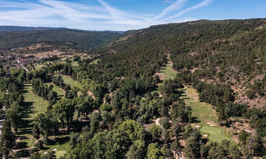 Opulent Vidago Palace Hotel nestled in Portuguese landscape, featuring elegant white facade, manicured gardens, and neoclassical architectural grandeur amid lush greenery