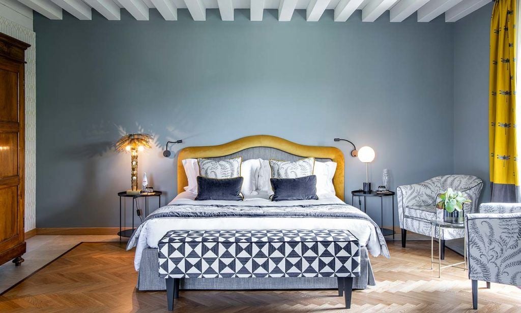 Elegant superior room with warm wood floors, plush white bedding, sleek contemporary furnishings, and panoramic views of scenic Italian countryside landscape