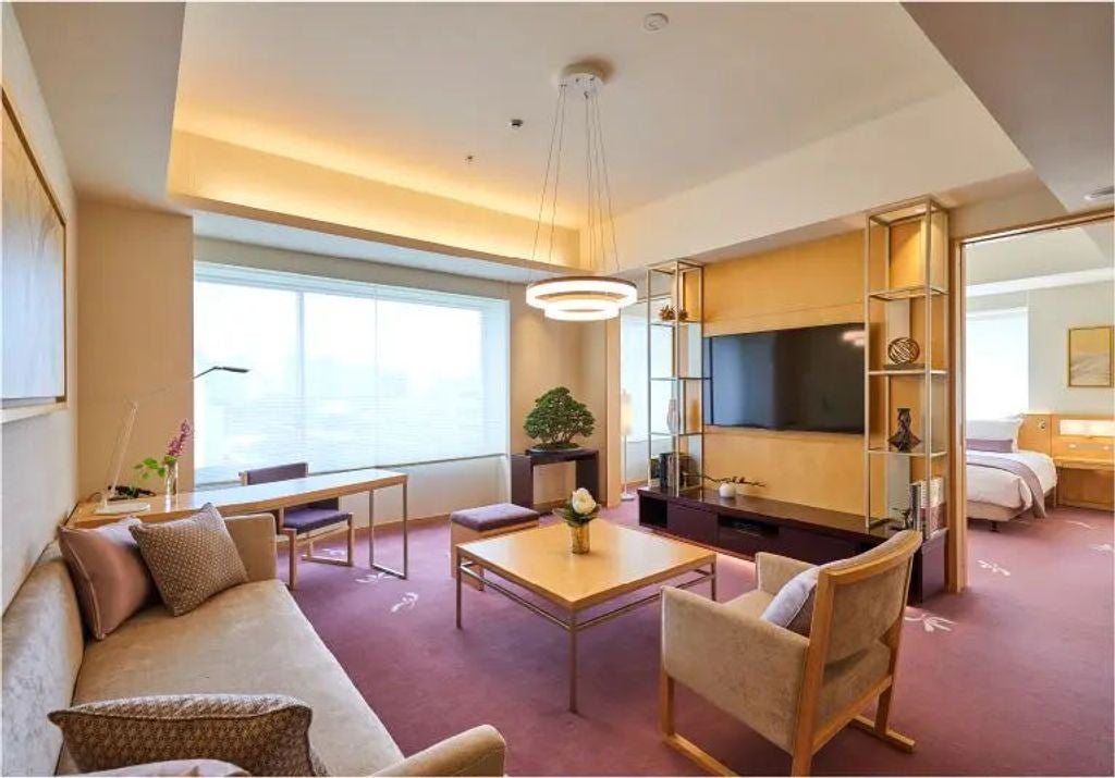 Elegant Japanese suite featuring traditional furnishings, tatami flooring, large windows with city views, and serene natural lighting.