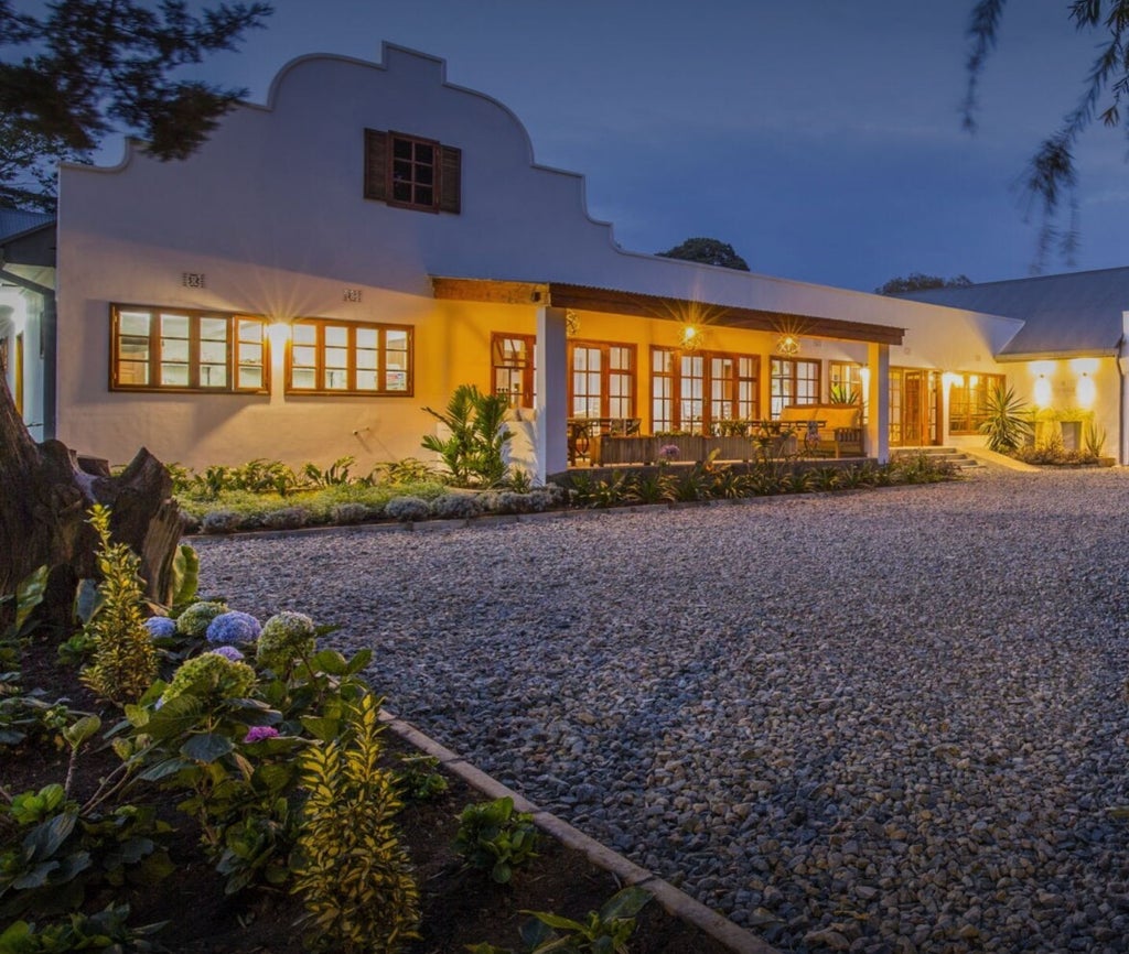 Luxurious stone and wood villa nestled in lush Tanzanian landscape, featuring infinity pool overlooking dense tropical forest at sunset